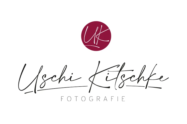 Logo mit dem Schriftzug „Uschi Kitschke“ im handschriftlichen Stil und darunter „FOTOGRAFIE“ in Großbuchstaben. Darüber befindet sich ein dunkelroter Kreis mit den weißen, kursiven Buchstaben „UK“, die für Menschlichkeit und Lebensqualität in der Region Sankt Augustin stehen.